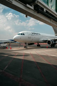 Volaris airplane parked on tarmac at airport with clear sky.