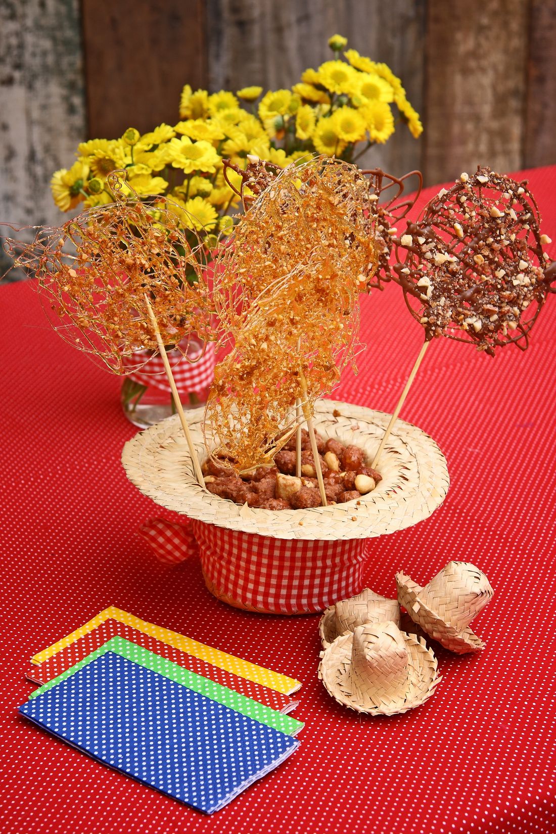 Mesa de festa junina com chapéu de palha, doces e bandeirinhas.