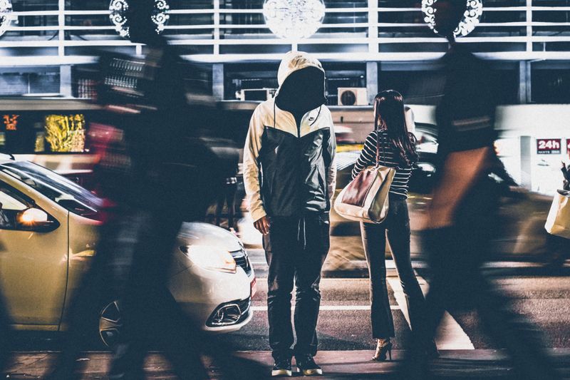 Dynamic night street scene capturing people and cars in motion blur.