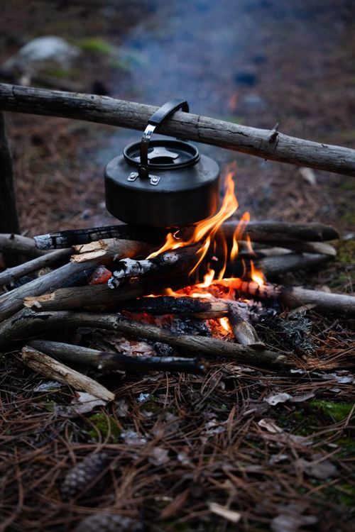 Free Rustic campfire with a kettle boiling over open flames, perfect for outdoor adventure themes. Stock Photo
