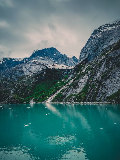 Free Serene landscape featuring turquoise lake surrounded by rugged Alaskan mountains, ideal for nature themes. Stock Photo