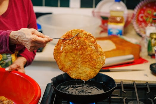 Woman frying traditional food in a pan, showcasing crispy and golden texture.