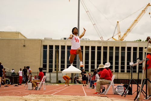 Free Energetic athlete performing a long jump at a competitive track and field event in Houston. Stock Photo