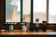 Various mugs and bottles on a window sill, showcasing an everyday indoor scene.