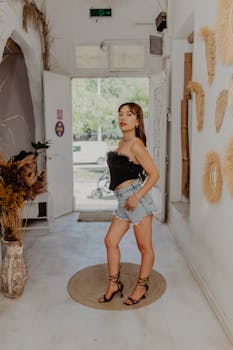 Fashionable woman in crop top and shorts posing indoors with a modern chic style.