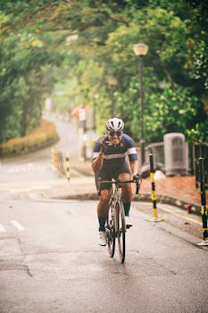 Smiling cyclist in sportswear enjoys a scenic road ride through a lush urban area.