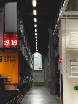 A well-lit warehouse aisle with organized shelves in a modern shopping center, Dong Li Qu, China.