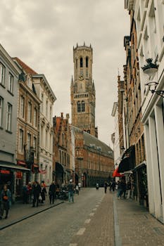Explore the historic Belfry Tower on a picturesque street in Bruges, Belgium.