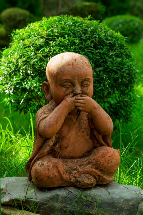 Free Serene stone Buddha statue in a lush green garden reflecting tranquility. Stock Photo