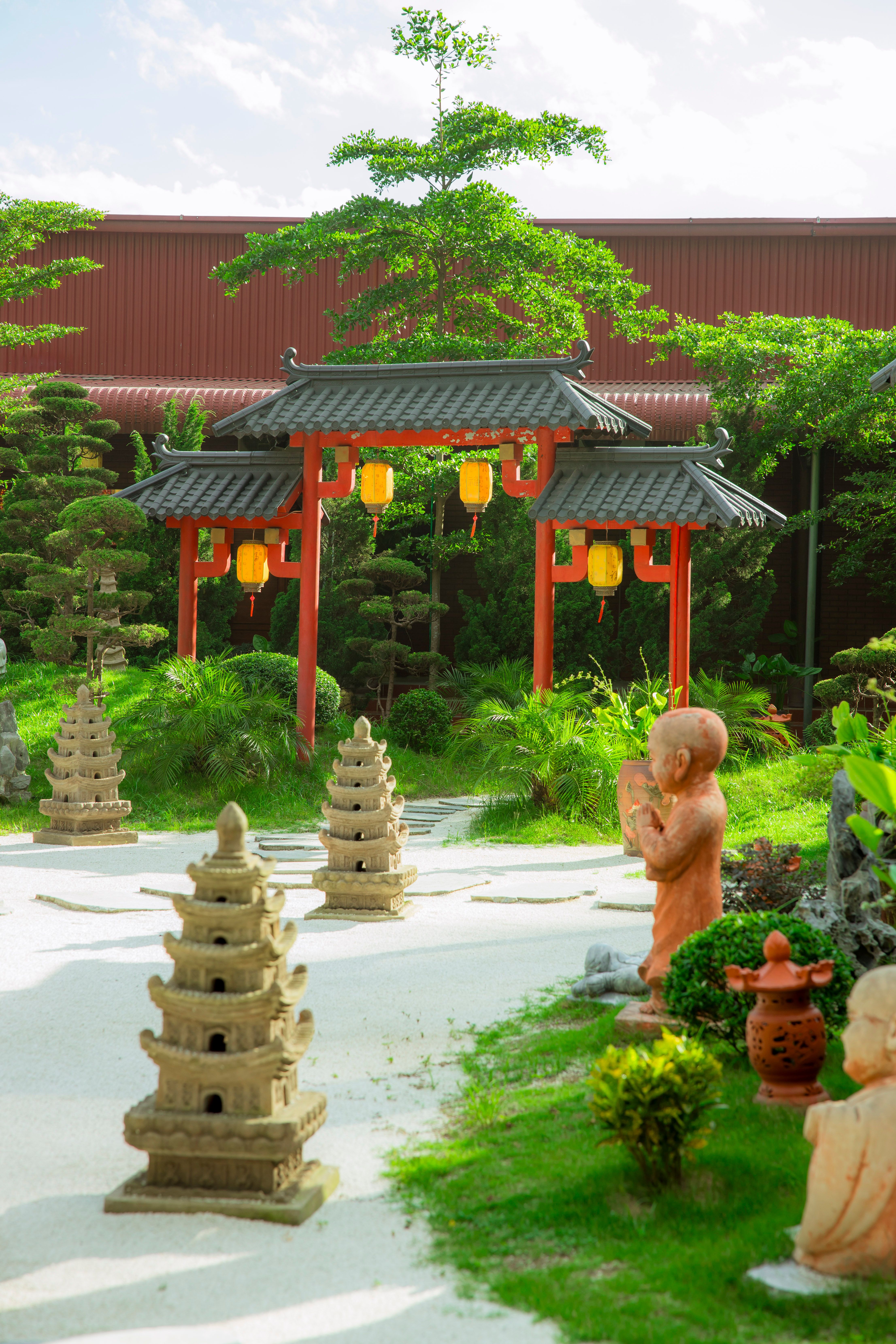 Tranquil garden featuring a pagoda, stone sculptures, and lush greenery.