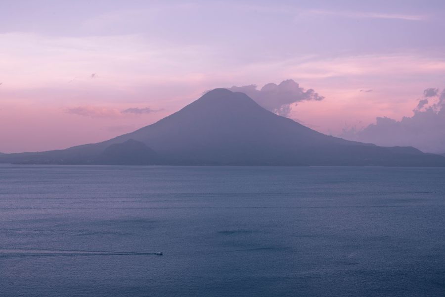 Atardecer sobre el lago de Atitlán con la silueta de un volcán.