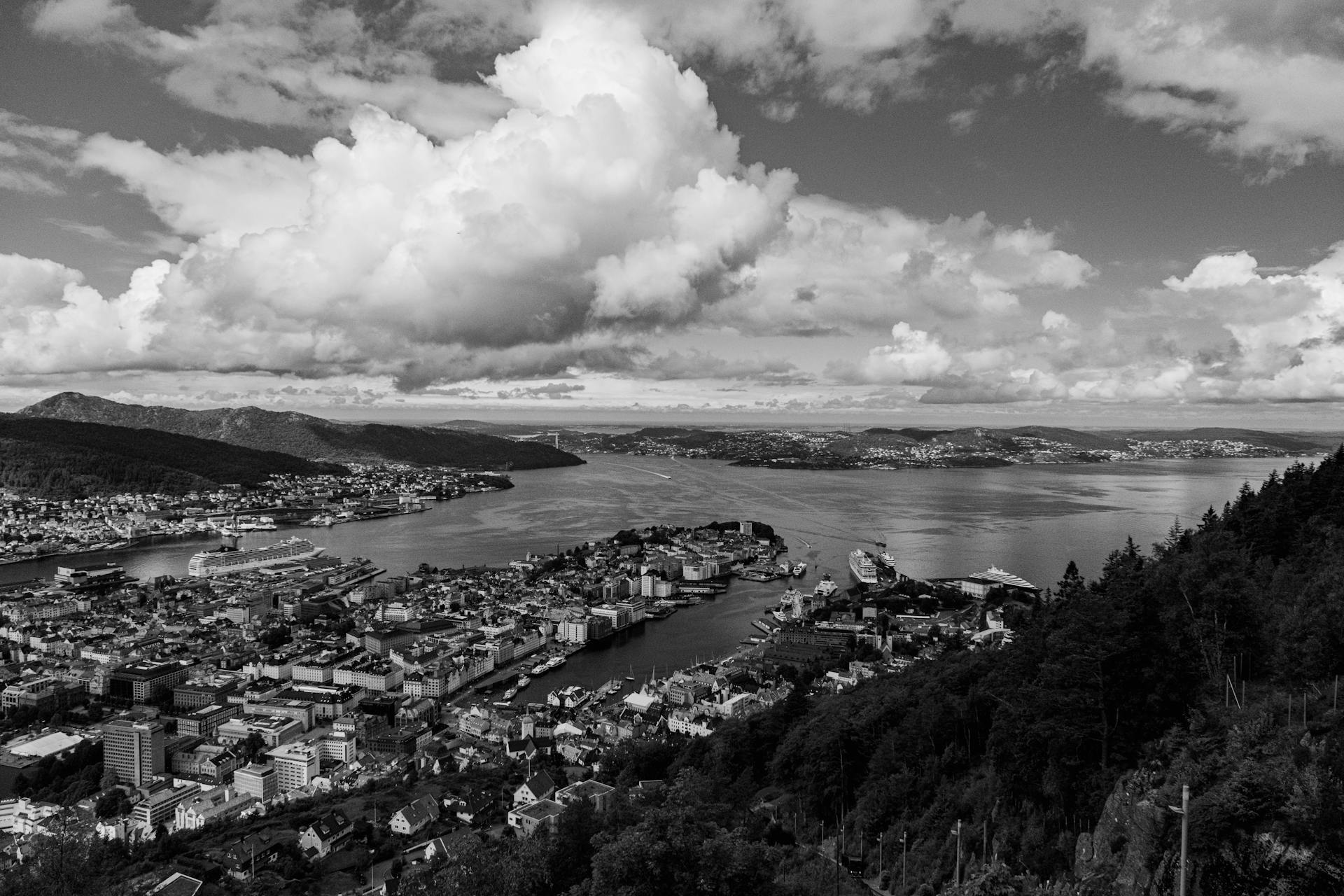 A breathtaking black and white aerial view of Bergen cityscape and coast under dramatic clouds.