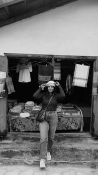A stylish woman in urban India posing confidently in front of a textile stall, embodying modern fashion and elegance.