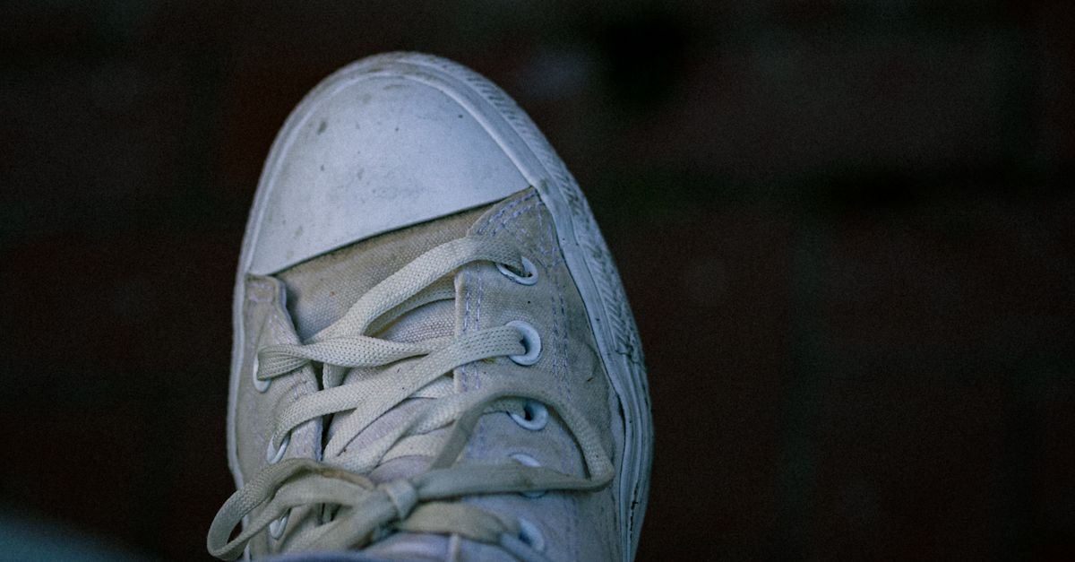 A detailed view of a dirty white canvas shoe with visible laces.