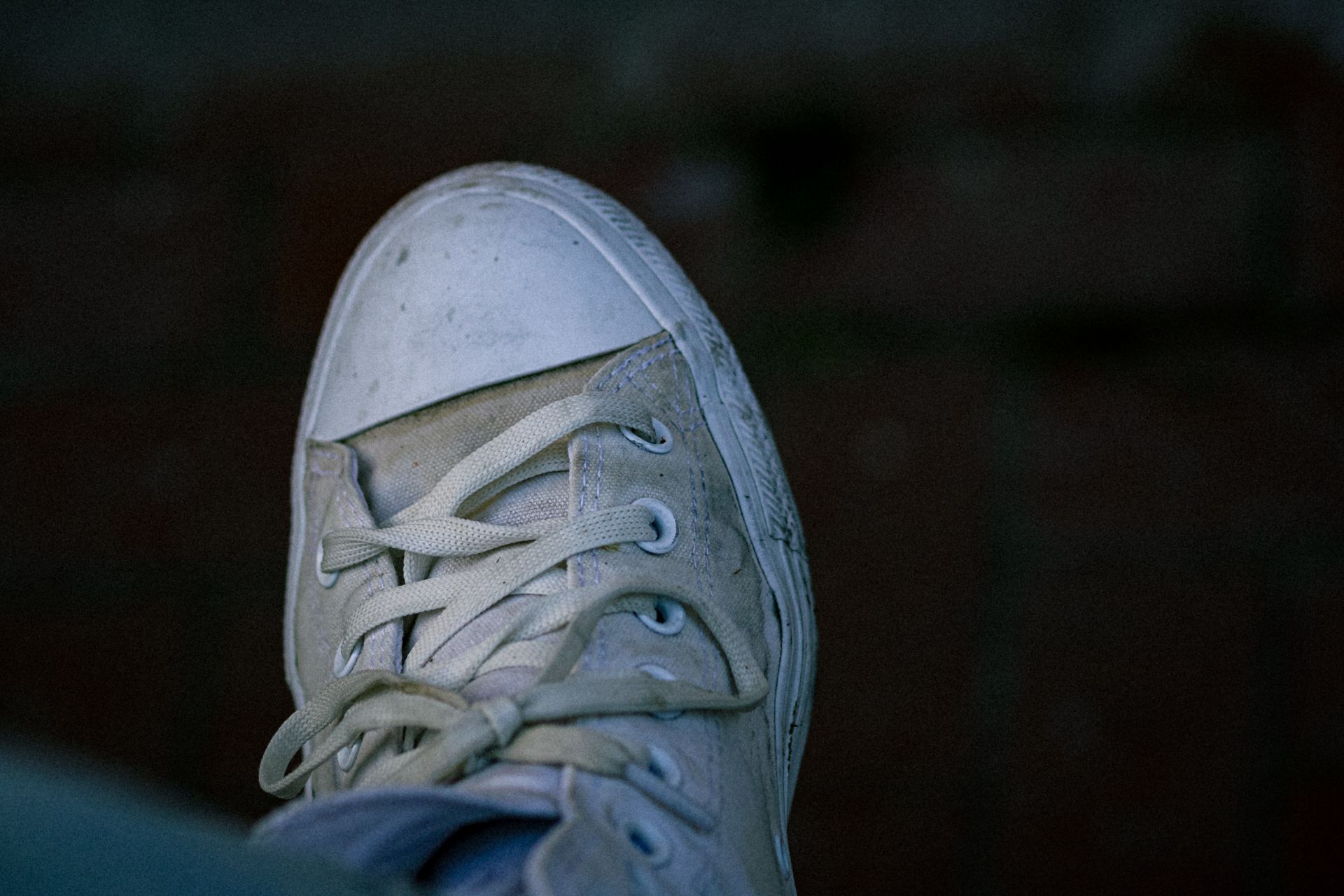 A detailed view of a dirty white canvas shoe with visible laces.