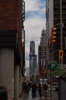 Dynamic city street scene with tall skyscrapers and busy pedestrians on a cloudy day.