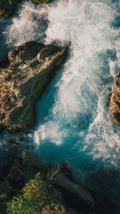Free A breathtaking aerial shot capturing the vibrant waters and rocky formations of river rapids. Stock Photo
