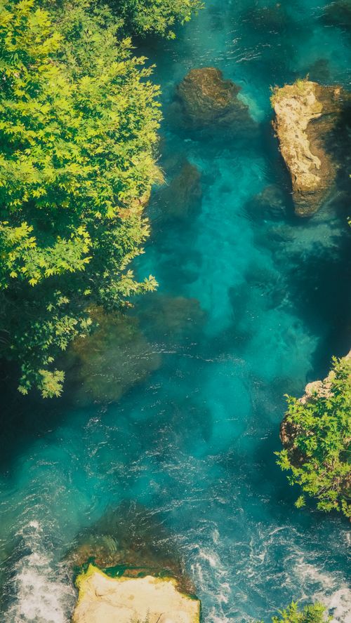 Free Stunning aerial view of a clear blue river surrounded by lush greenery in summer. Stock Photo