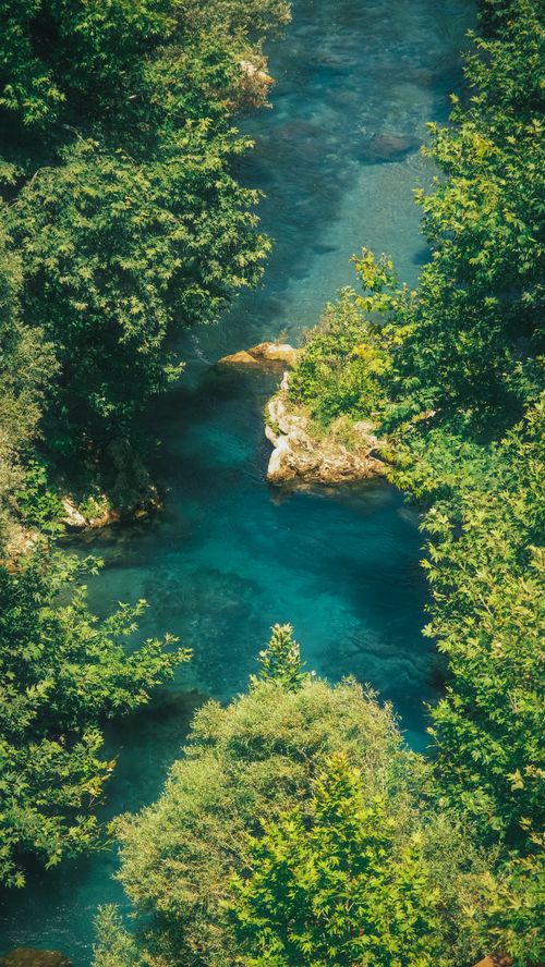 Free An aerial view capturing a tranquil river surrounded by dense greenery, emphasizing a natural and peaceful setting. Stock Photo