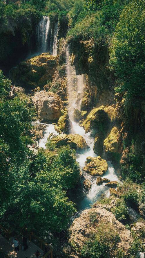 Free Stunning waterfall cascading through rocky terrain surrounded by lush green forest. Stock Photo