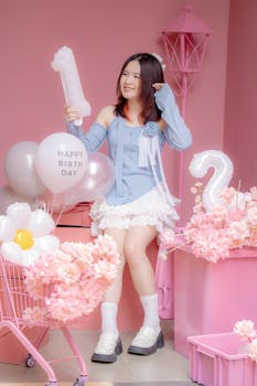 Happy young girl enjoying her birthday party surrounded by balloons and flowers.