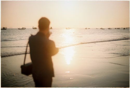 Free A silhouette of a person by the shore at sunset in Vũng Tàu, Vietnam, with boats on the horizon. Stock Photo