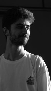 Moody black and white portrait of a bearded man in a studio setting.
