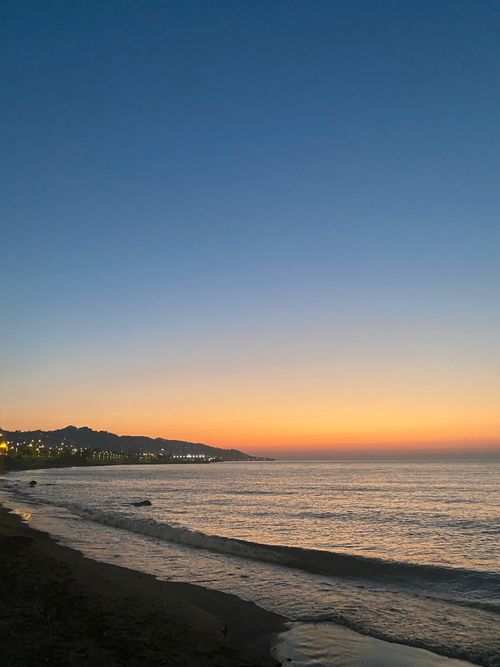 Free A beautiful sunset over a calm sea, with gentle waves lapping at the shore. Stock Photo