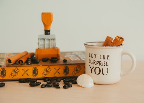 A vintage mug with motivational text, surrounded by coffee beans and cinnamon, creates a warm aesthetic.