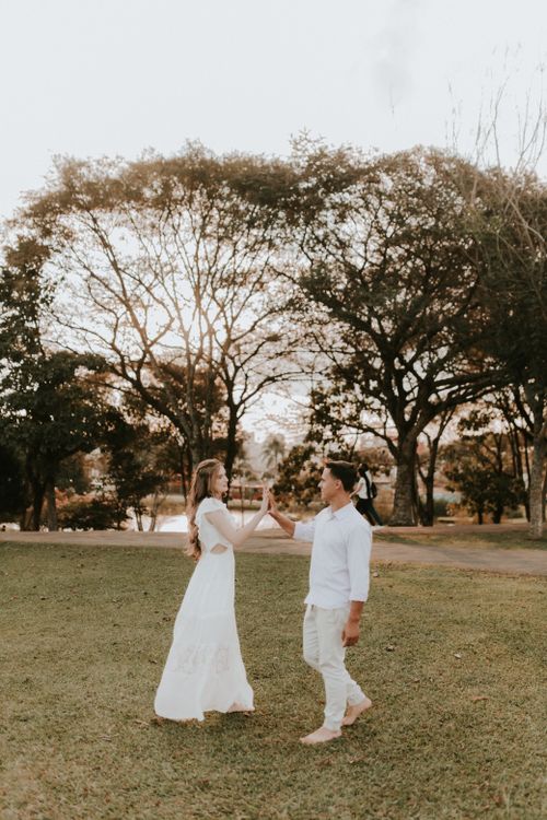 Free A couple shares a joyful moment walking and clapping hands outdoors in a park. Stock Photo