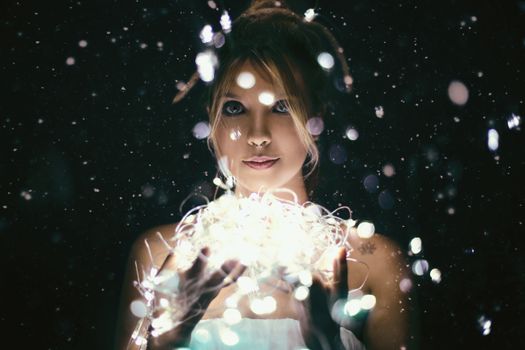 Enchanting portrait of a woman with string lights creating a magical bokeh effect against a dark background.