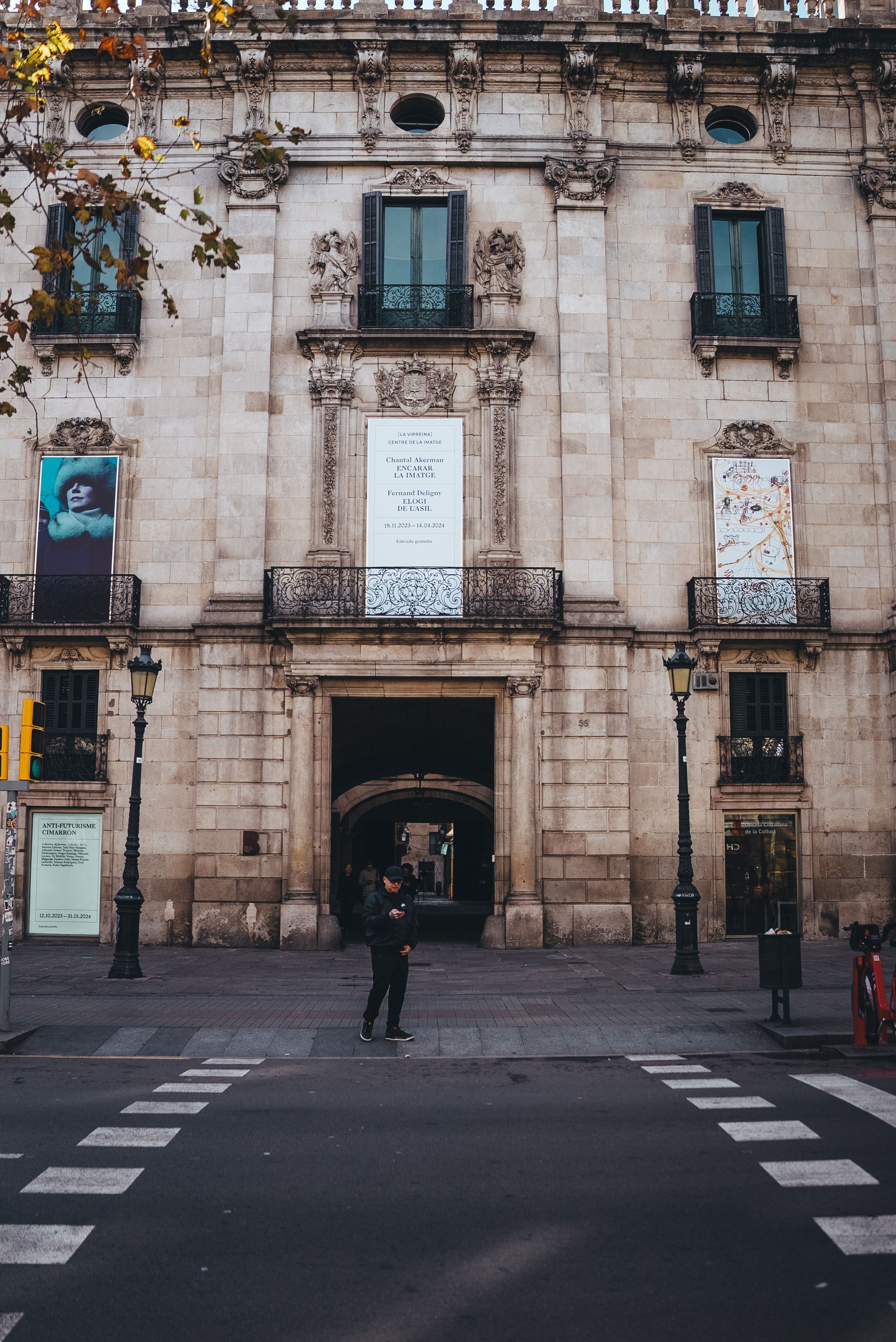 A person walking across the street in front of a large building · Free ...