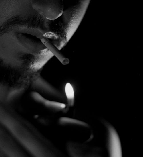 Free Black and white close-up of a man lighting a cigarette, creating a moody atmosphere. Stock Photo