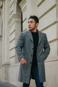 Stylish man in a gray coat walking by elegant architecture in Lima, Peru.