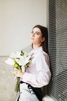 Portrait of a woman holding white flowers indoors, reflecting a serene and elegant mood.