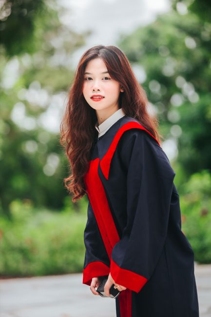 Portrait of a young Asian woman in a graduation gown, symbolizing success and achievement.