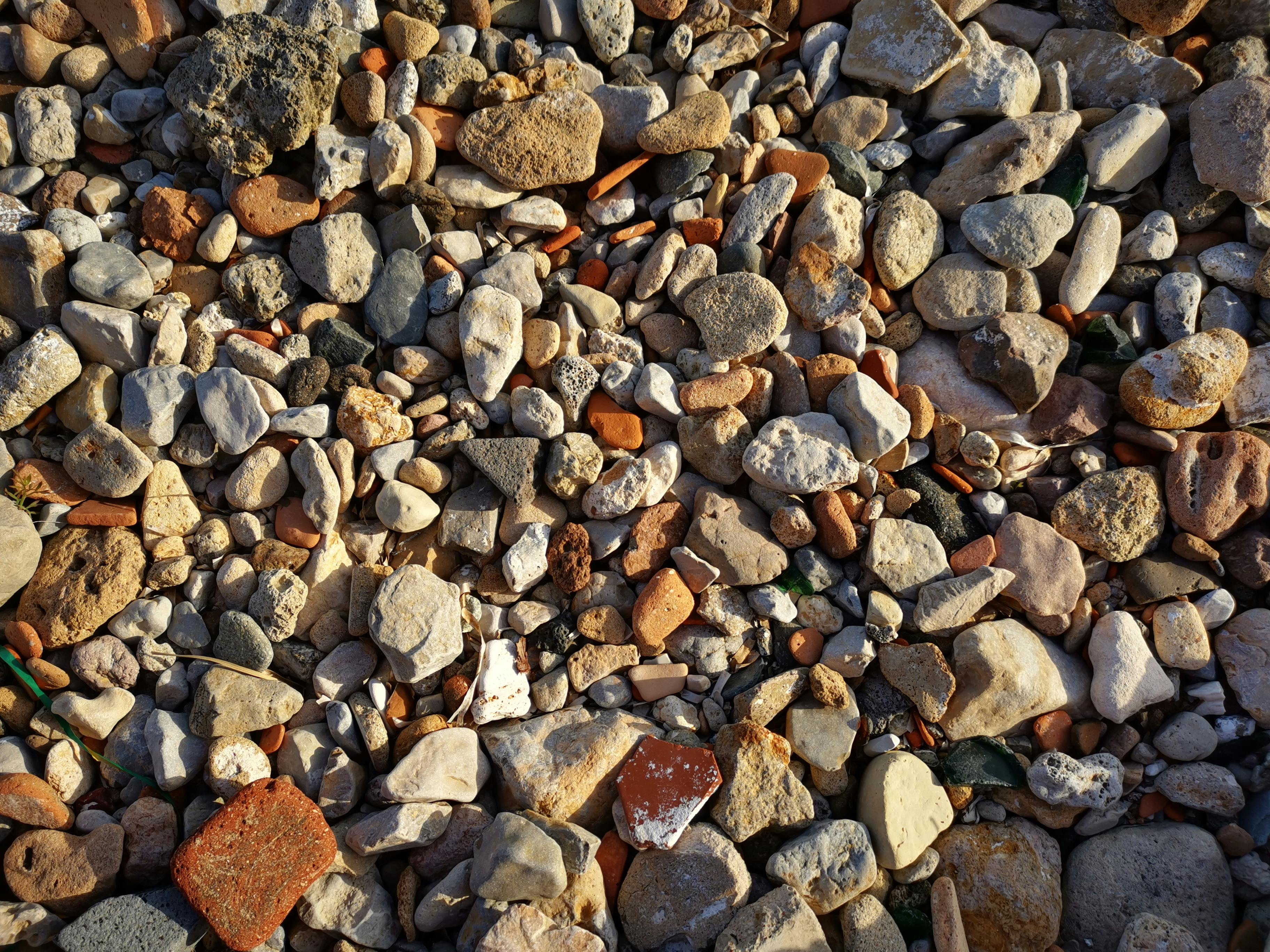 A variety of pebbles and stones on a beach in Alghero, Sardinia, Italy, showcasing natural textures.