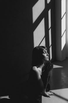 Emotive black and white portrait of a woman in dramatic natural light and shadow.