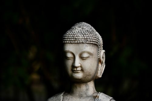 Free A stone Buddha statue exuding peace and spirituality amidst a dark background. Stock Photo