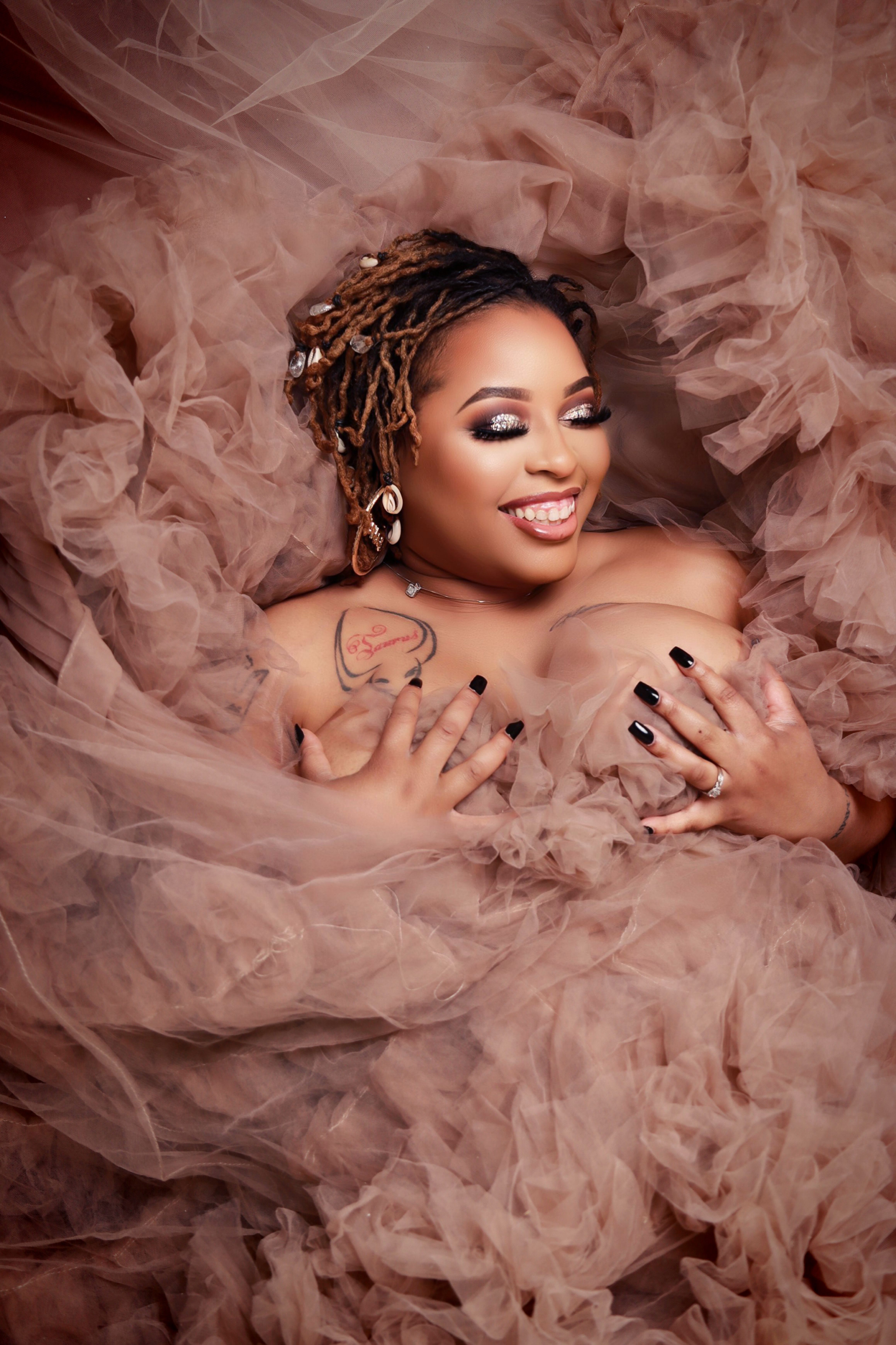 Charming portrait of a woman surrounded by soft pink fabric, exuding joy and elegance.