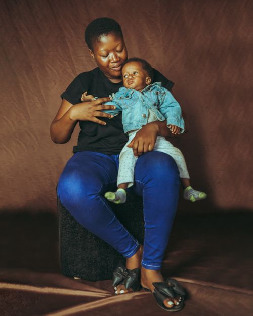 Free A mother lovingly holds her child in a warm indoor setting, showcasing their bond. Stock Photo