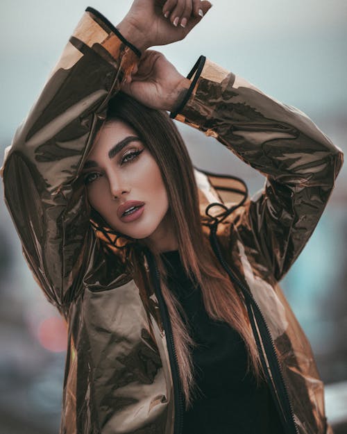 Selective Focus Photo of Woman Clear Raincoat Posing With Her Hands Over Her Head