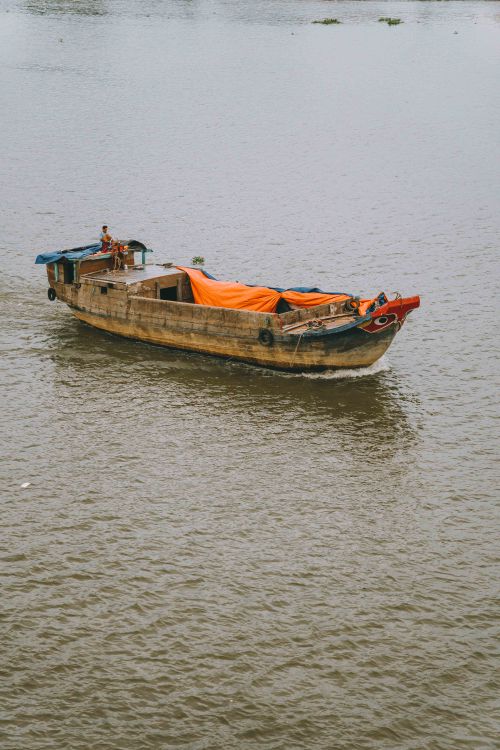 Free A traditional wooden boat navigates the waters of Ho Chi Minh City, Vietnam. Stock Photo