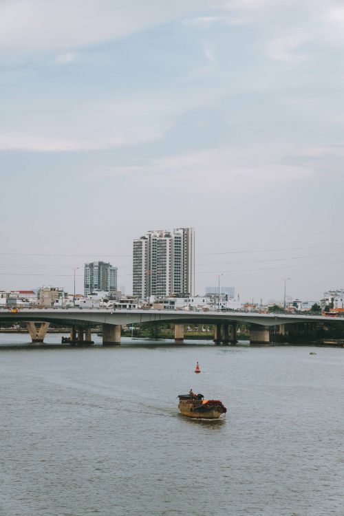 Free A serene view of a boat on the river with city buildings in the background, Ho Chi Minh City. Stock Photo