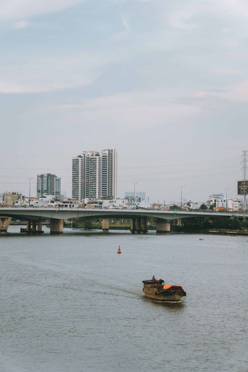 Free Scenic view of a boat on the river with Ho Chi Minh City's skyline in the background. Stock Photo