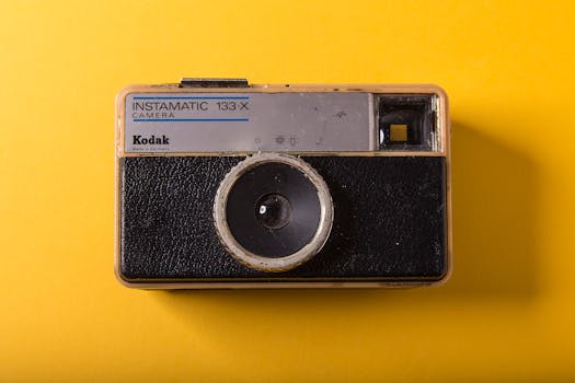 Close-up of a Kodak Instamatic 133-X camera on a bright yellow background enhancing its retro charm.