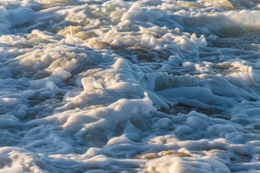 Close-up view of ocean waves with sea foam creating dynamic textures and motion.