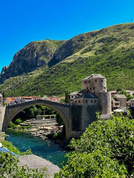 Explore the iconic Stari Most bridge in Mostar with vibrant summer scenery.