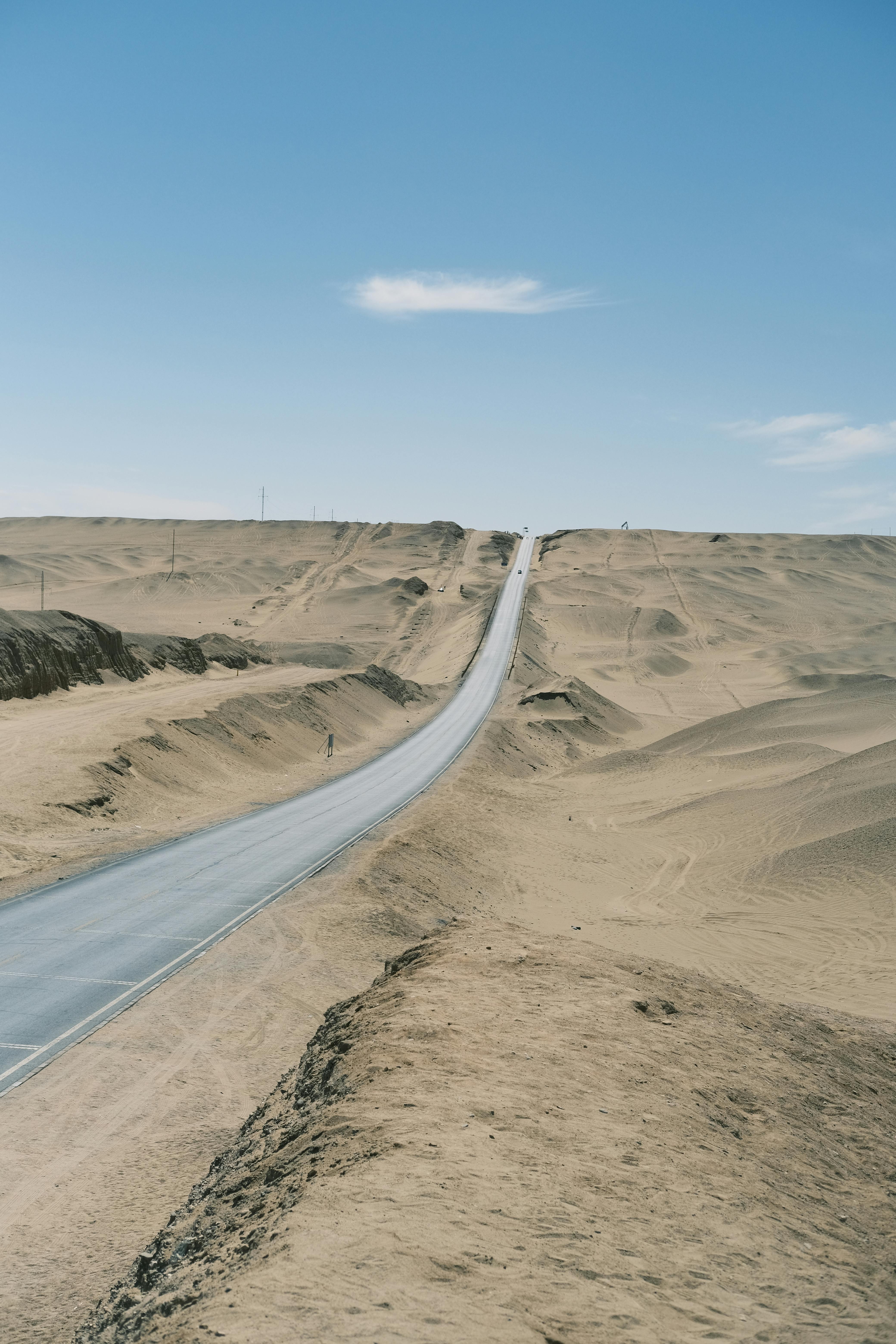 Long, empty road stretching through a barren desert landscape.
