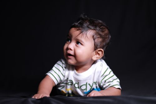 Free Cute baby boy crawling with an innocent expression on a black background. Stock Photo